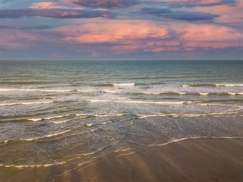 Vista aérea do zangão das ondas do mar na praia ao pôr do sol Foto