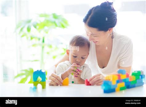 Asian Mother And Baby Boy Playing With Colorful Blocks Toy In White