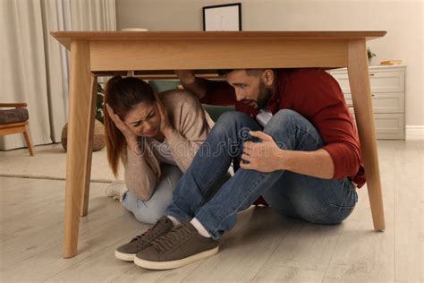 Scared Couple Hiding Under Table In Living Room During Earthquake Stock Image Image Of