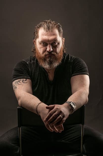 Premium Photo Portrait Of Man Sitting Against Black Background