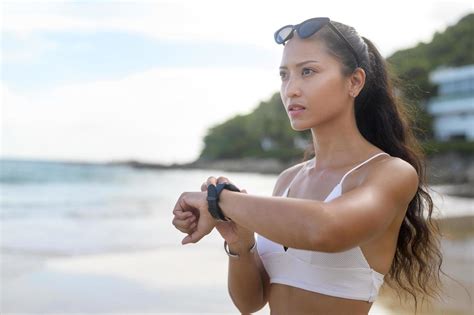 jeune belle femme en bikini se détendre et utiliser une smartwatch sur la plage l été les
