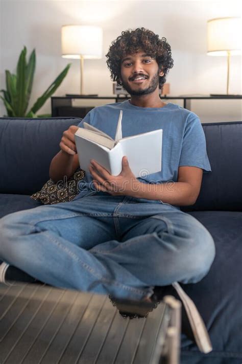 Un Indio De Cabello Rizado Leyendo Un Libro Y Mirando Involucrado Foto