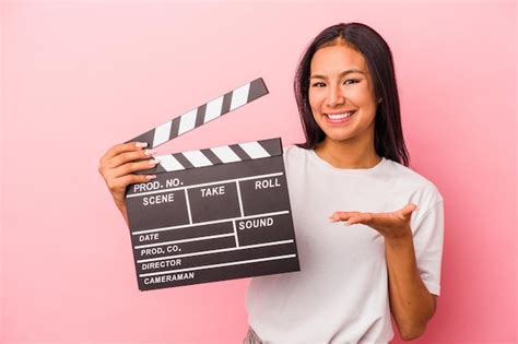 Jovem mulher latina segurando a claquete isolada no fundo rosa mostrando um espaço de cópia na