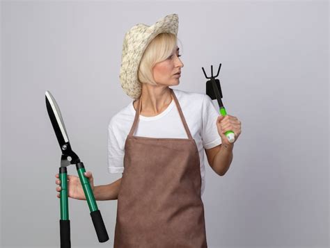 Une Jardinière Blonde D âge Moyen Impressionnée En Uniforme Portant Un Chapeau Tenant Des