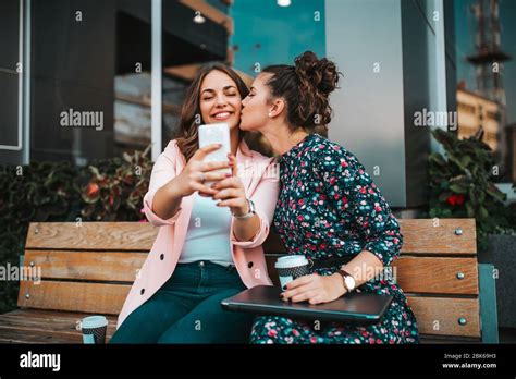 Two Joyful Cheerful Girls Taking A Selfie While Sitting Together In The