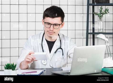 Male Doctor In White Coat With Stethoscope Over His Neck Sitting At