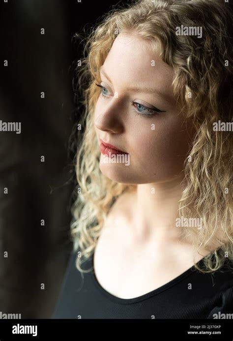 Window portrait of a 21 year old white blonde woman with curling hair ...