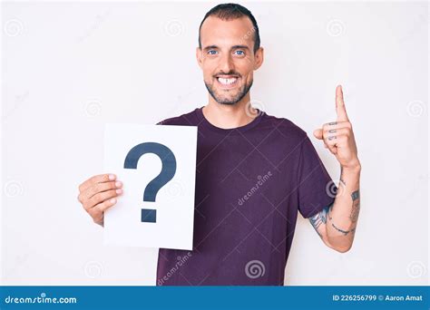 Young Handsome Man With Tattoo Holding Question Mark Surprised With An Idea Or Question Pointing