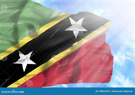 St Kitts And Nevis Waving Flag Against Blue Sky With Sunrays Stock