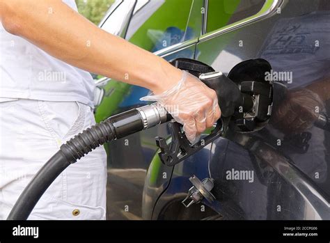 A Man Refueling A Black Car With Diesel Fuel At A Gas Station