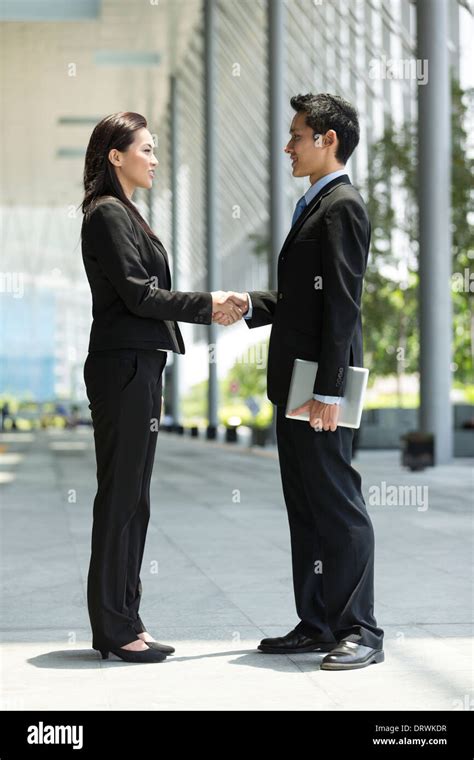 Chinese Businessman And Businesswoman Shaking Hands Outside The Office