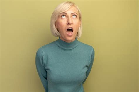 Choqué jolie blonde femme slave lève les yeux isolé sur mur vert olive Photo Gratuite