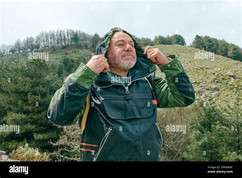 Mature Bearded Traveler Man Hiking In Mountain Forest Wearing Jacket