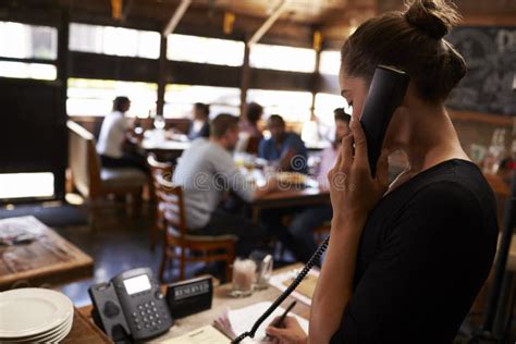 Giovane Donna Che Prende Una Prenotazione Dal Telefono Ad Un Ristorante