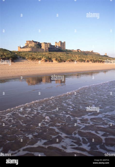 Historical Coastal Bamburgh Castle Landscape Reflection In Sandy Beach