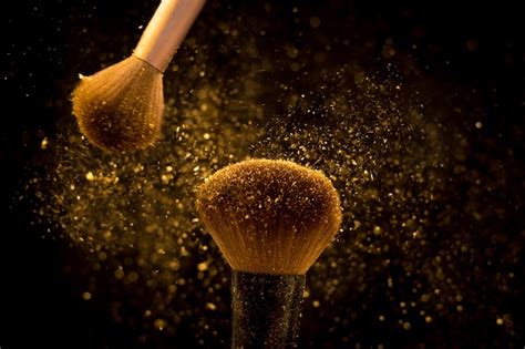 Makeup Brush With Golden Cosmetic Powder Spreading On Black Background