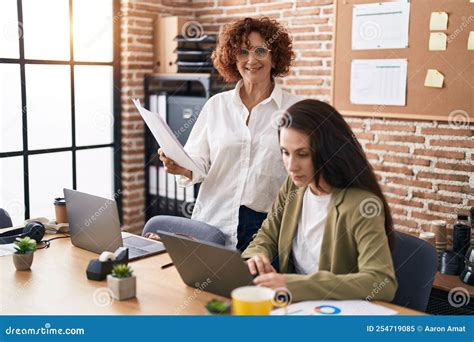 Two Women Business Workers Using Laptop Reading Document At Office