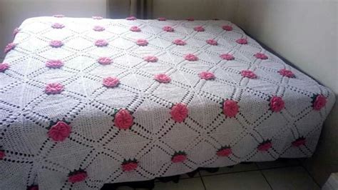 A White Crocheted Bedspread With Pink Roses On It And A Window In The