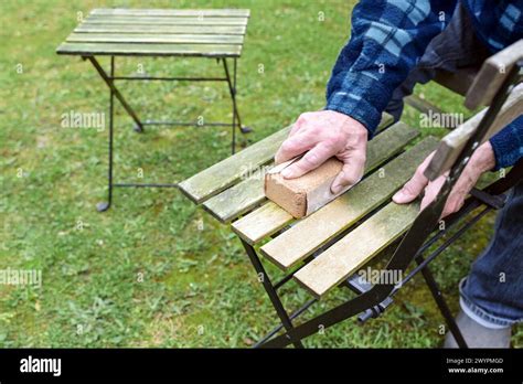 Man Is Cleaning And Restoring Wooden Outdoor Furniture Sanding The
