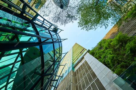 Premium Photo Low Angle Shot Of Modern Glass Buildings And Green With Clear Sky Background