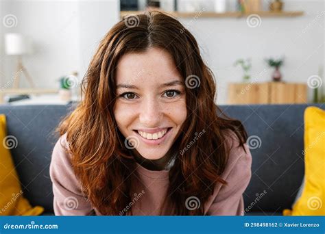 Portrait Of Young Redhead Girl Smiling At Camera Sitting On Sofa At