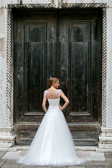 A Woman Standing In Front Of A Door Wearing A Wedding Dress With An