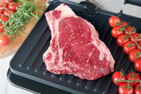 Premium Photo | Raw prime steaks on electric grill Black angus prime ...