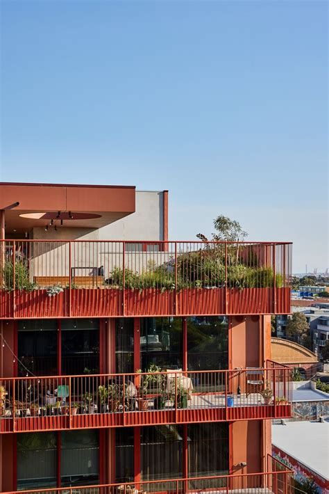 An Apartment Building With Red Balconies And Plants On The Balconies Above