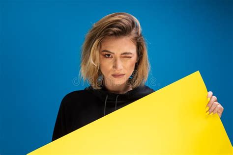 Portrait Of Dark Blonde Woman Winking While Holding Cardboard Paper