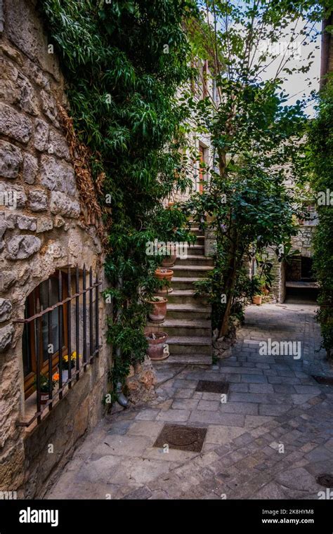 Narrow Cobblestone Street And Stairs With Lush Plants In The Village Of