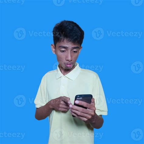 Young Asian Man Surprised Looking At Smart Phone Wearing Yellow T