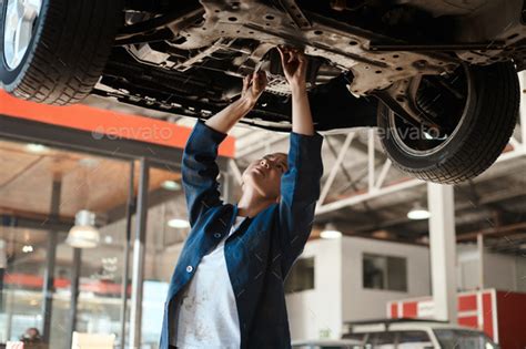 Shot Of A Female Mechanic Working Under A Lifted Car Stock Photo By