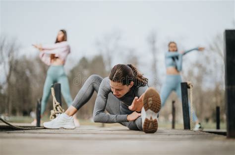 Female Athletes Stretching In Outdoor Workout Focused On Fitness And