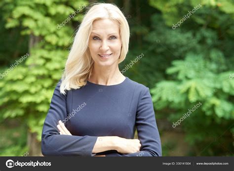 Smiling Mature Woman With Folded Arms Standing Outdoor Stock Photo By Gzorgz