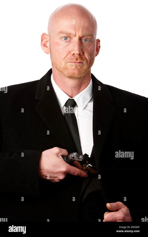 Bald Headed Man Wearing Heavy Black Overcoat Showing Revolver In Inside