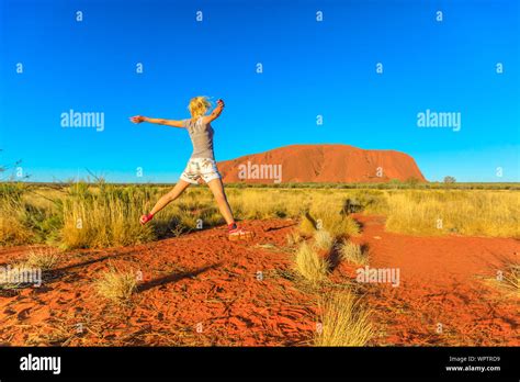 Happy Tourist Woman Jumping At Uluru Ayers Rock In Uluru Kata Tjuta