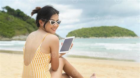 joven hermosa mujer en bikini relajándose y usando tableta en la playa verano vacaciones