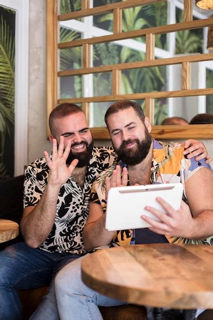 Casal gay sorridente de férias fazendo uma chamada de vídeo de um tablet conceito de conexões
