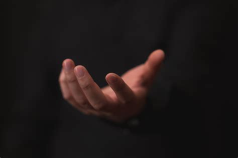 Hand Outstretched In Gesture Of Giving Or Receiving Black Background