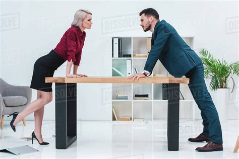 Side View Of Young Business People Leaning At Table And Looking At Each