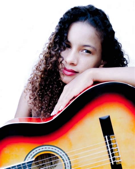 A Woman With Curly Hair Is Holding An Acoustic Guitar