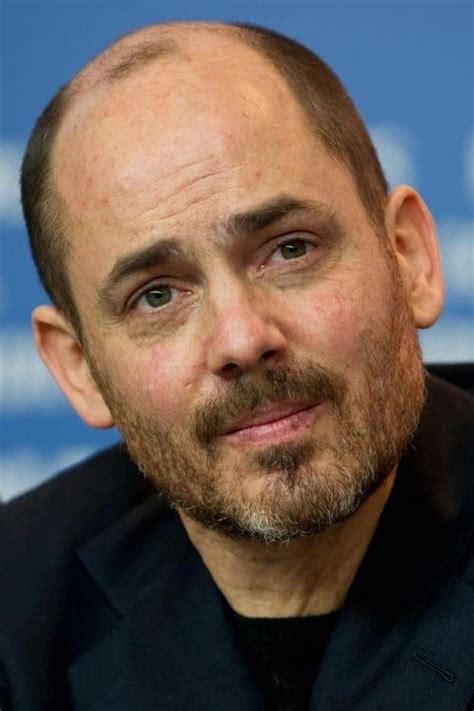 a close up of a person wearing a suit and tie with a balding head