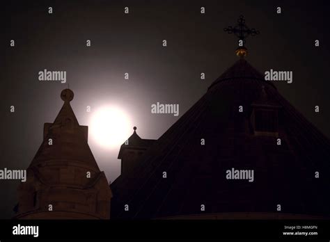 The Rising Full Moon Passes Behind The Dome And Bell Tower Of The