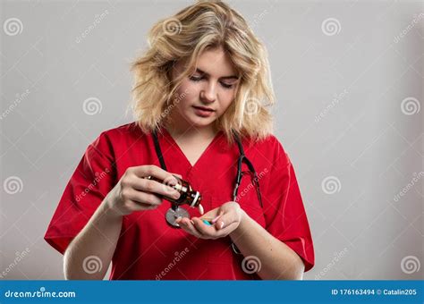 Portrait Of Female Nurse Wearing Red Scrub Spilling Pills Stock Photo