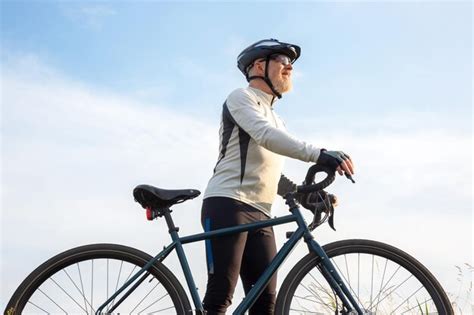 Premium Photo Bearded Man Cyclist Stands With A Bike Against The Blue