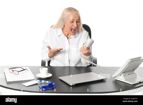 Angry Mature Secretary Talking By Phone At Table On White Background Stock Photo Alamy