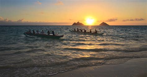 Two Outrigger Canoes Paddle Out From Shore At Sunrise In Hawaii Royal