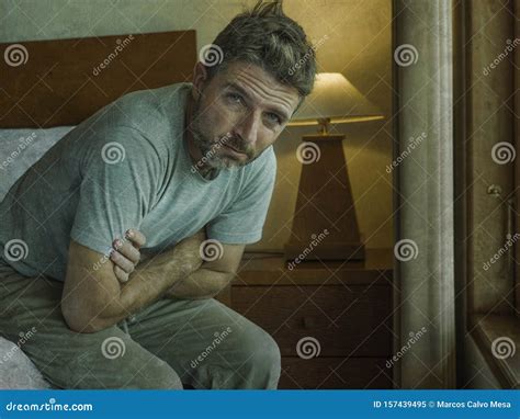 Dramatic Lifestyle Portrait Of Handsome Man Sitting Sad On Bed Feeling