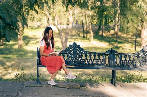 Premium Photo Mujer Latina Sentada En Una Banca De Un Parque Leyendo