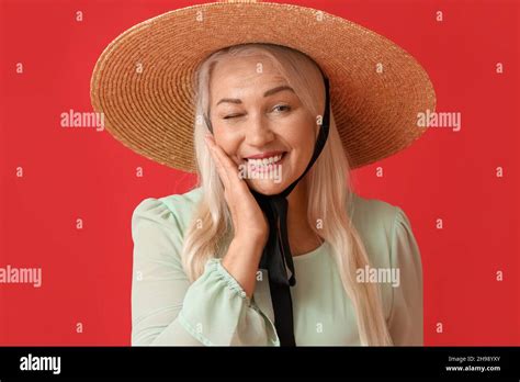 Smiling Mature Woman In Straw Hat Winking On Red Background Stock Photo Alamy